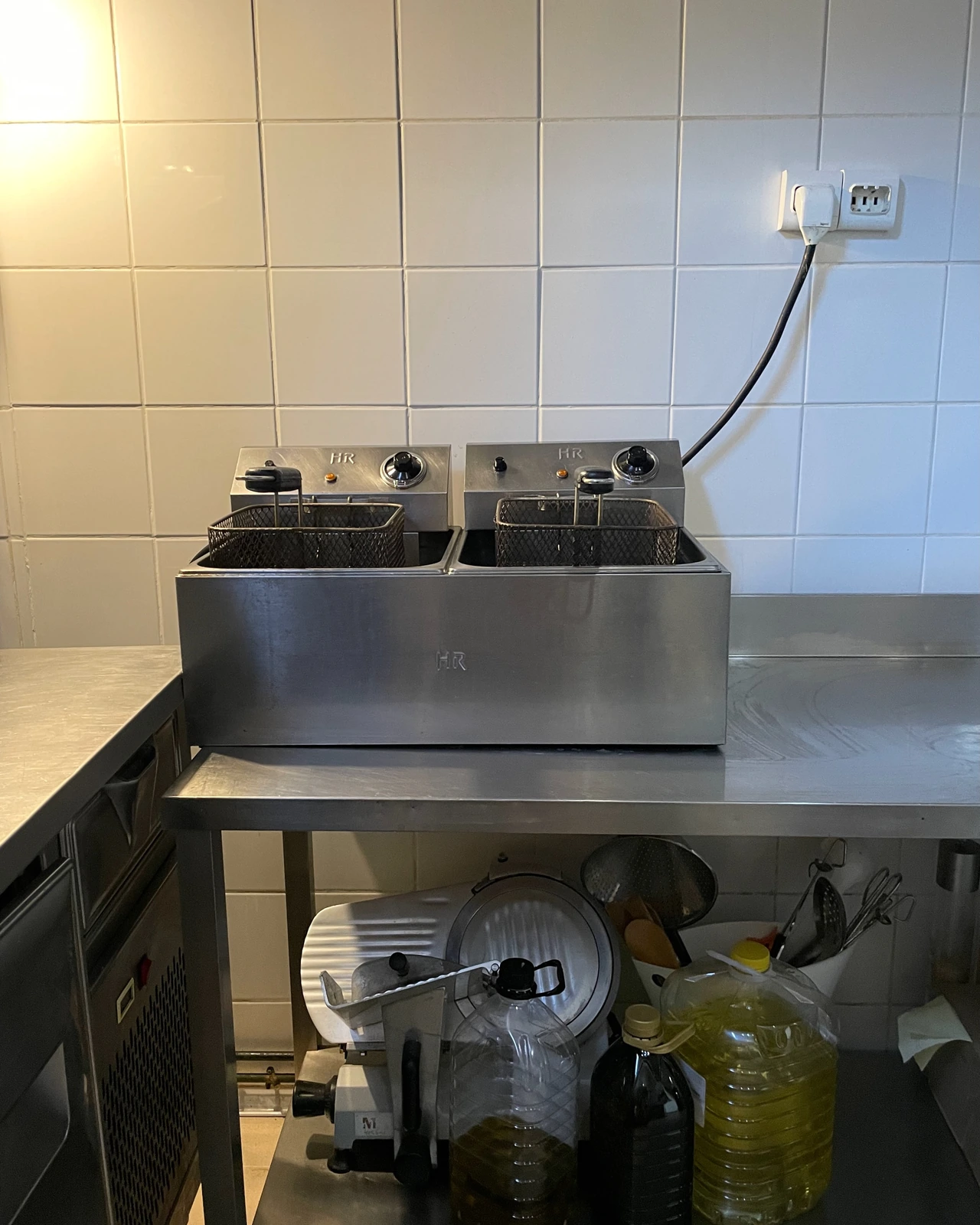 Freidora doble sobre mesa de acero inoxidable con almacenaje debajo