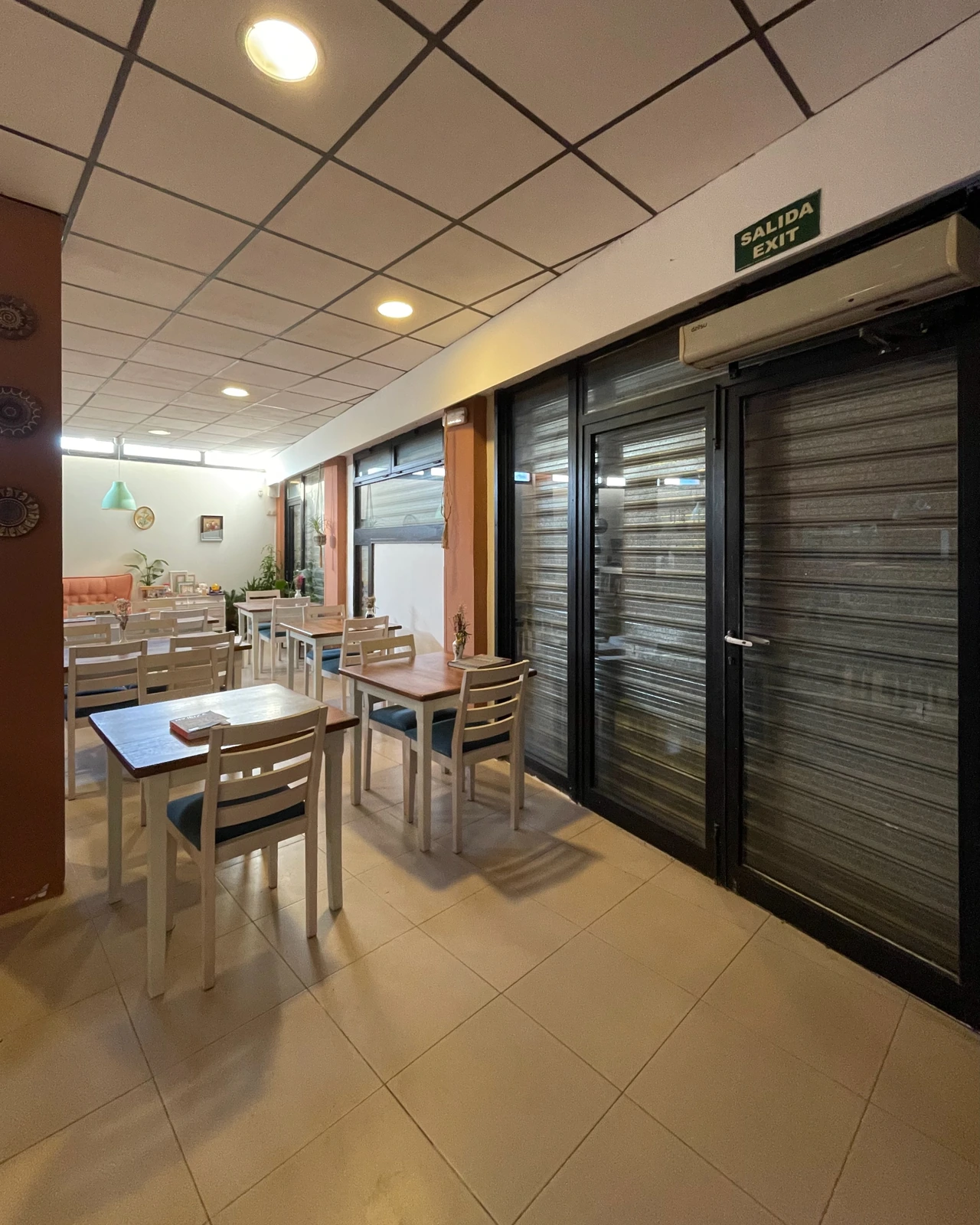 Vista interior de mesas y sillas con persianas de seguridad instaladas en las ventanas